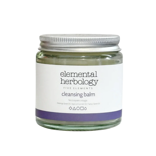 Elemental Herbology Five Elements Cleansing Balm in a clear glass jar with a silver metal lid and a white label featuring a purple band at the bottom.